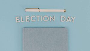 Blue notebook and pen against a light blue background reading 'Election Day', ideal for campaign themes.
